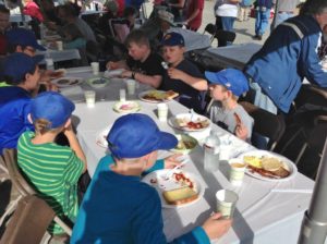 children eating breakfast under tent