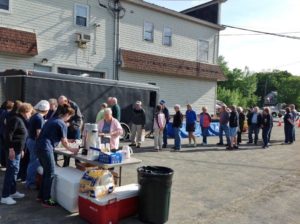 employees serving breakfast to a long line of event attendees