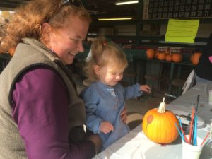 woman and child decorating pumpkin