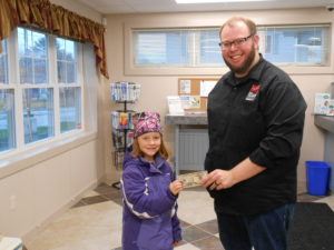 employee handing prize to young girl