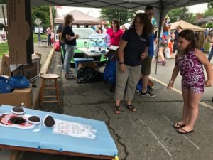 young girl at festival playing cornhole game