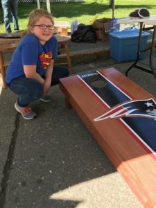 young girl posing in front of New England Patriots cornhole game that she won