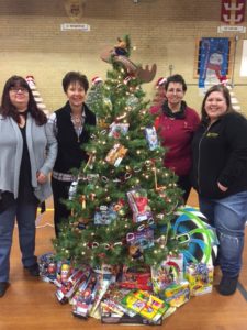 Four employees posing around decorated Christmas tree