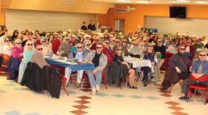 crowd of people sitting at tables wearing sunglasses