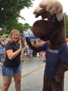 Monty Moose high-fiving a girl at the festival
