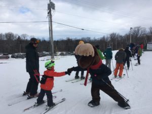 Monty Moose fist bumping with young skier