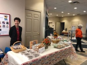 employee standing a table of baked goodies