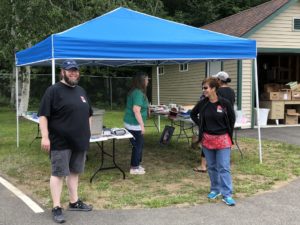 employees ready to help with yard sale at canopy with yard sale items