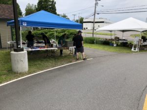 Two canopies set up with yard sale items and several employee volunteers