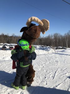 Monty Moose hugging young skiier